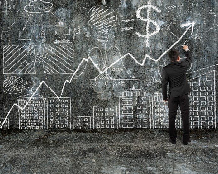 businessman drawing business concept doodles on old concrete wall