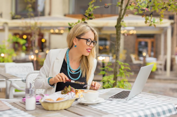 Business woman eating lunch and working on laptop