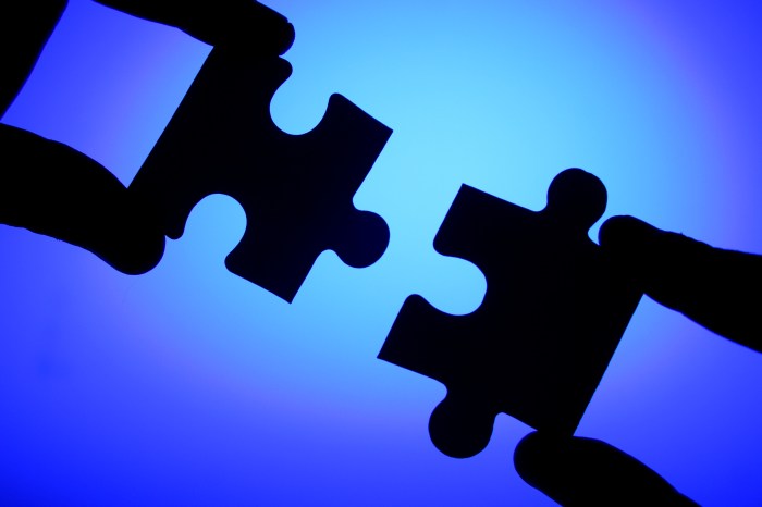 Hands connecting two jigsaw puzzle pieces